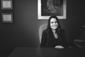 Anita Dhar Miller in office at desk smiling black & white