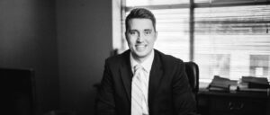 Ben Erickson in an office with a shaded window behind him black & white