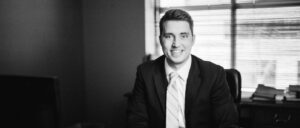 Ben Erickson in an office with a shaded window behind him black & white