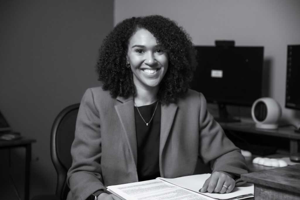 Nadia Valentine behind a desk smiling with paperwork